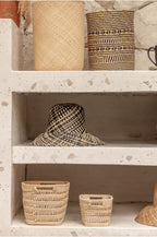 Woven rattan hats and baskets on a rustic wooden shelf