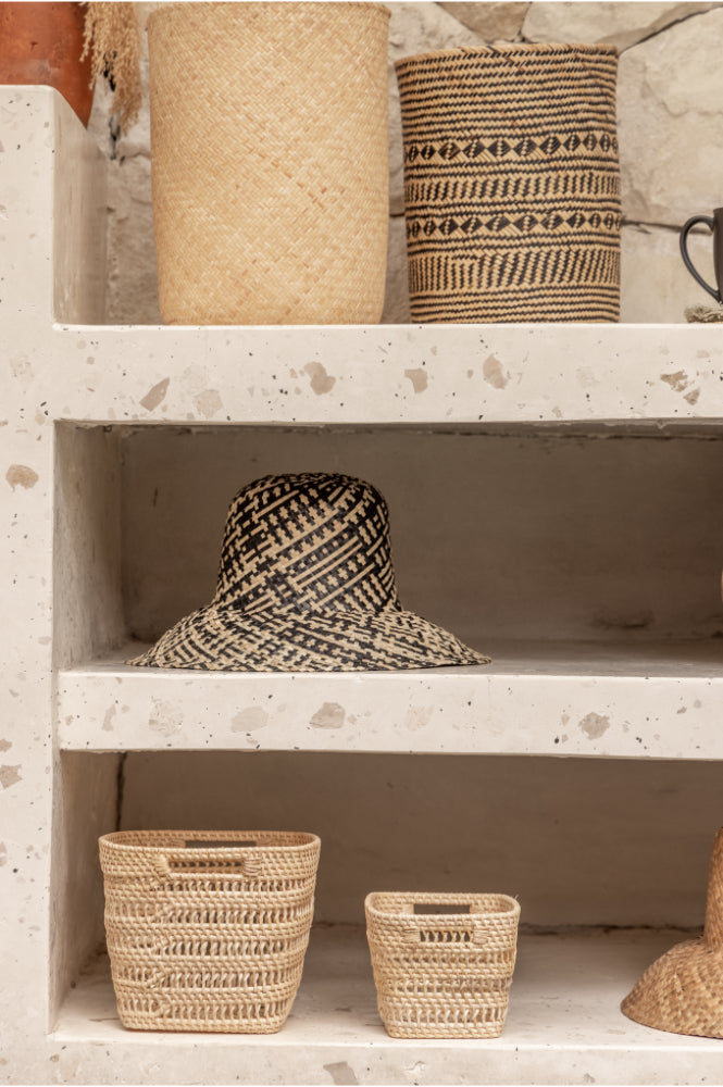 Woven rattan hats and baskets on a rustic wooden shelf