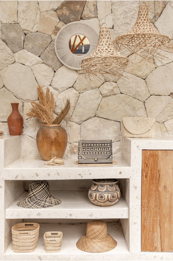 Decorative interior setting with stone wall, shelves with decorative items, and woven lamps and baskets.