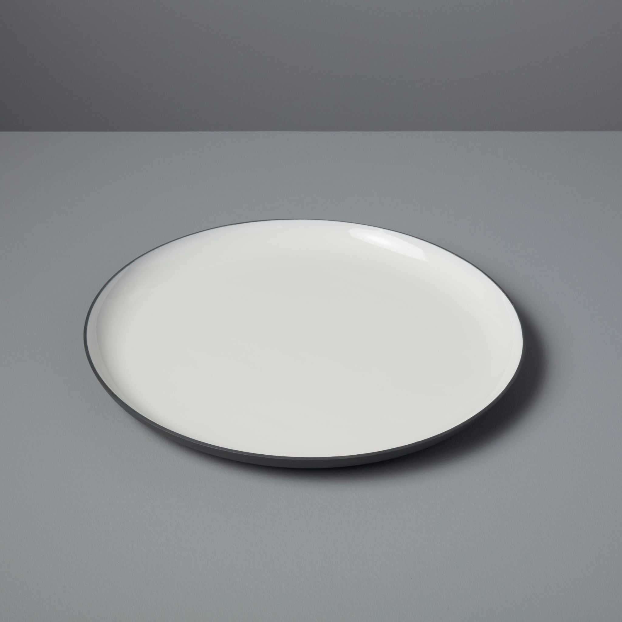 White plate with black rim on a gray background
