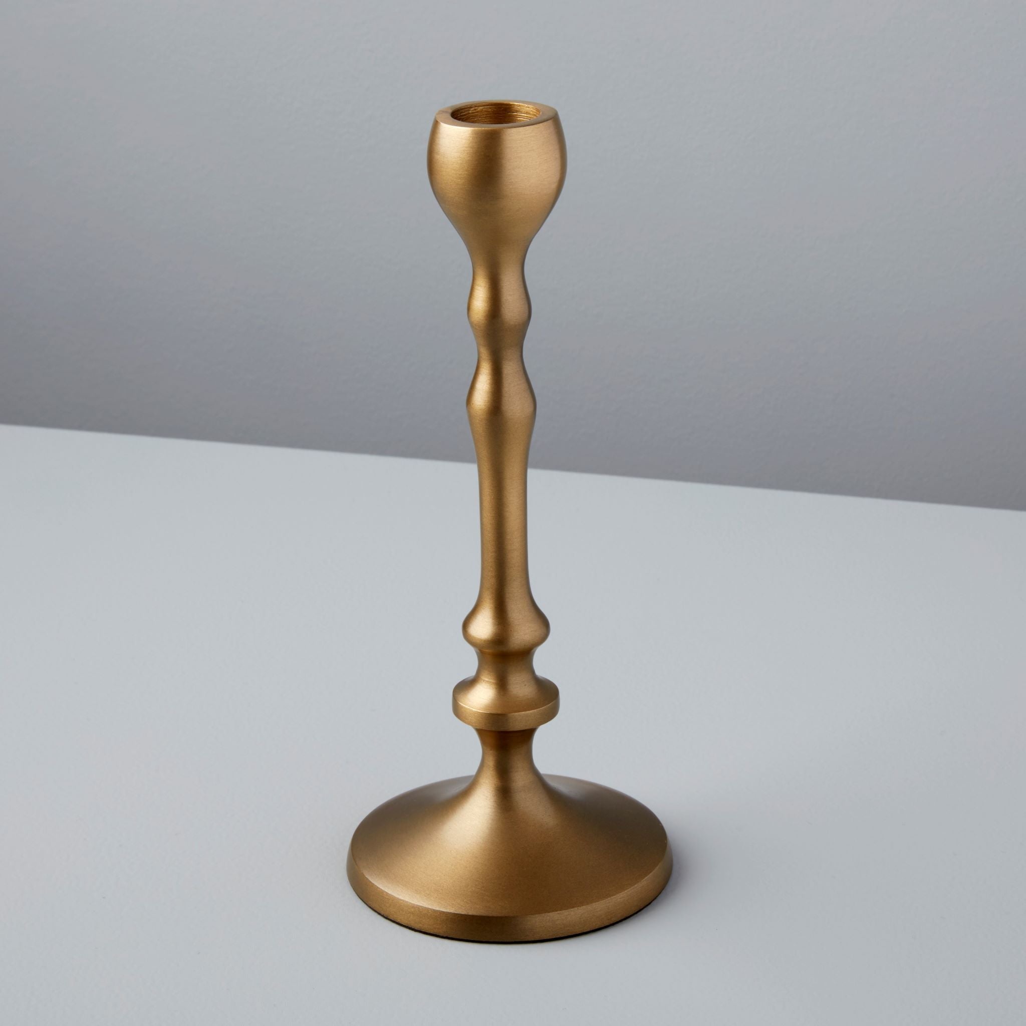 Gold candle holder on a gray background