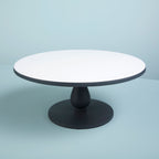 Round cake stand with white top and black base on a light blue background