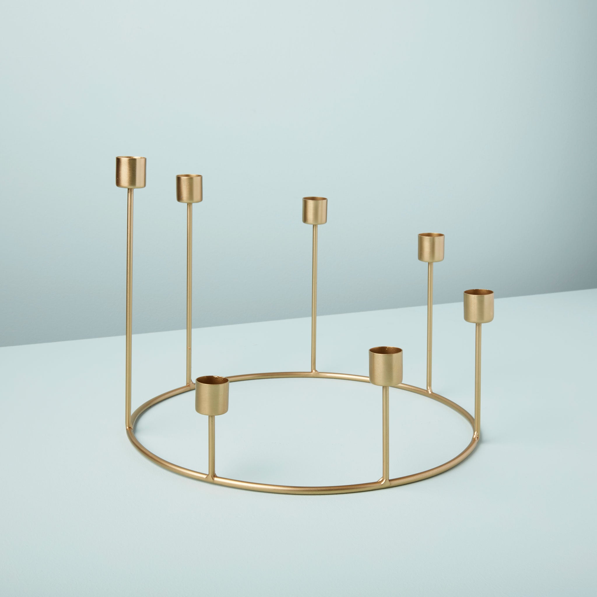 Gold metal candle holder on a light blue background