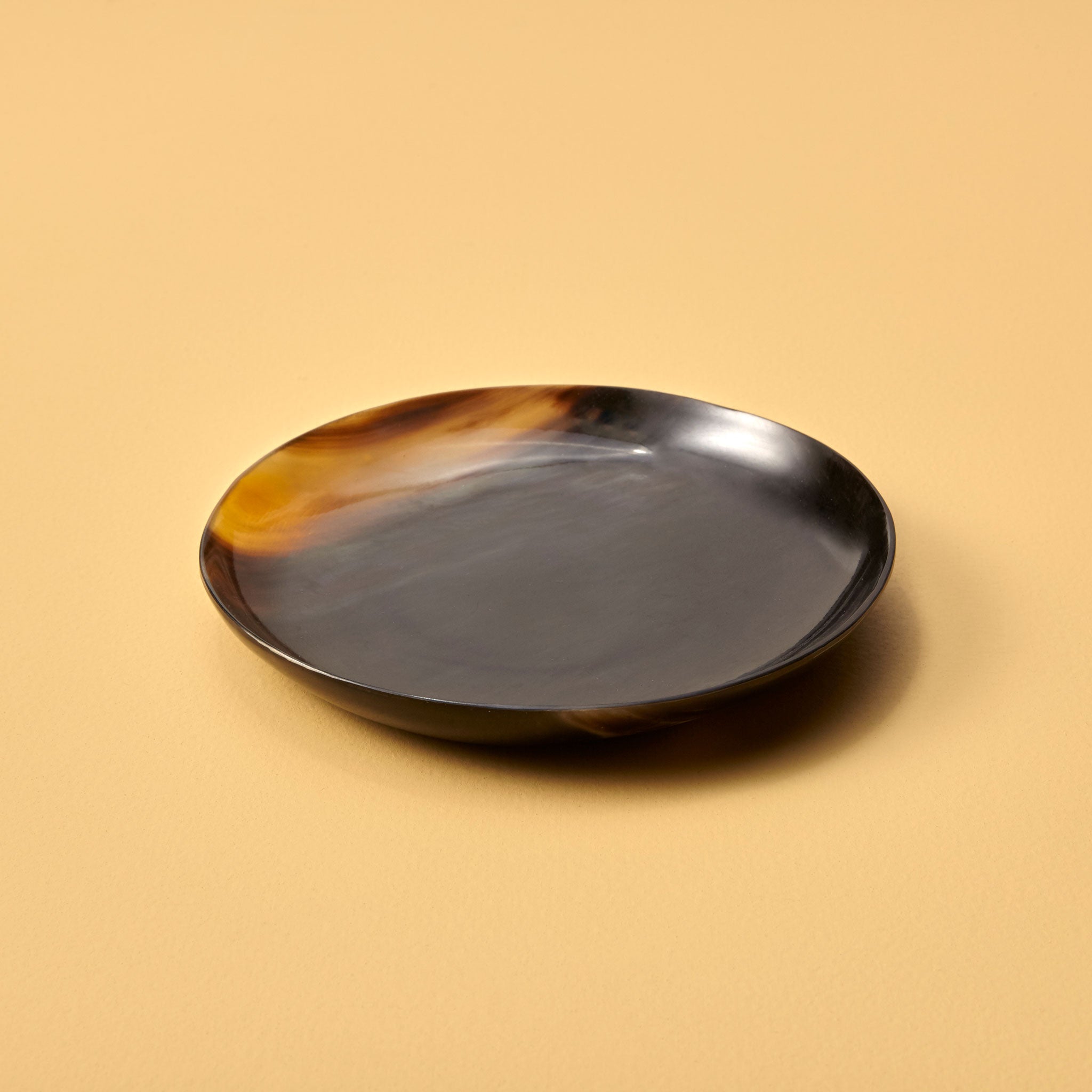 Round ceramic plate with tortoiseshell pattern on a beige background