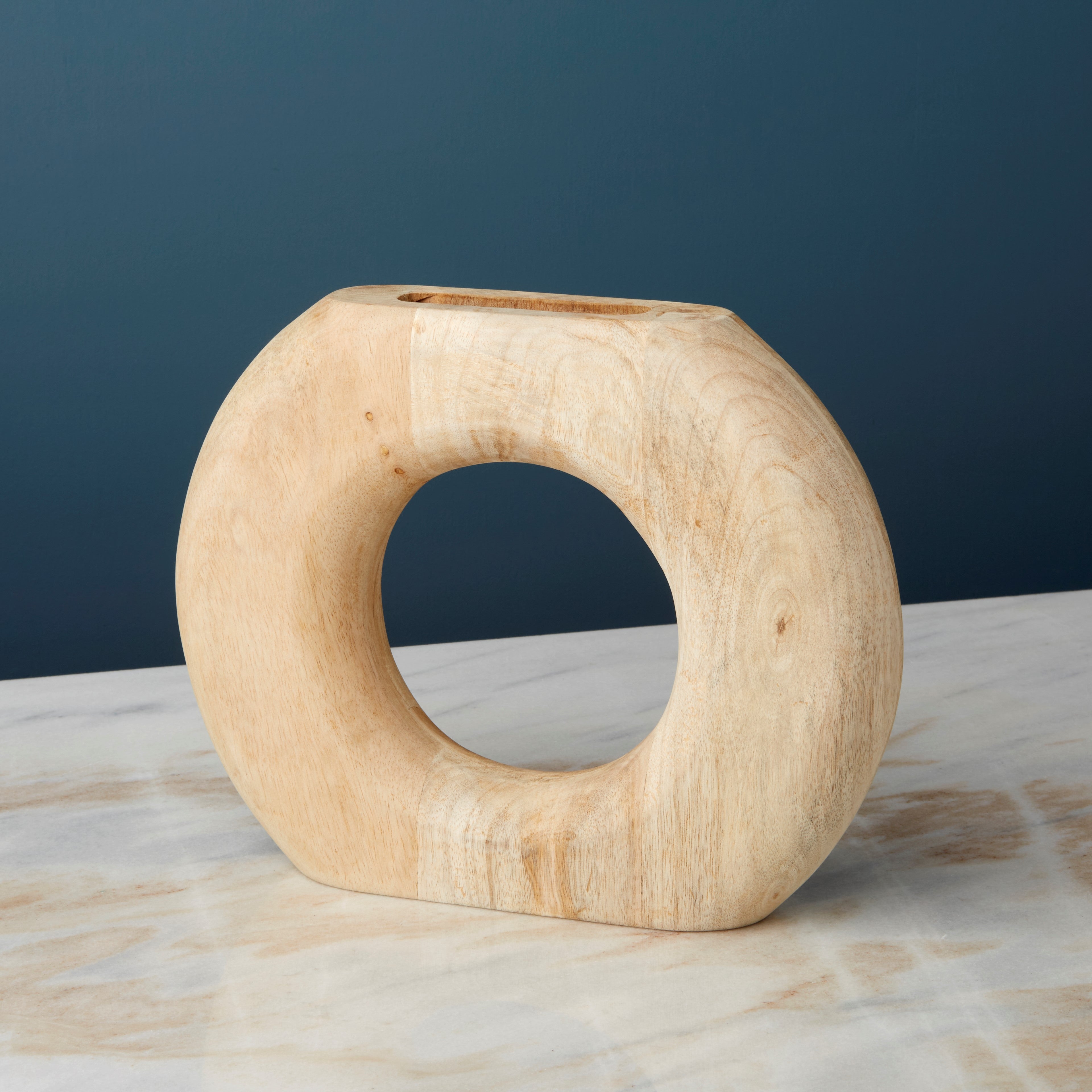 Wooden ring-shaped vase on a marble surface with a dark blue background