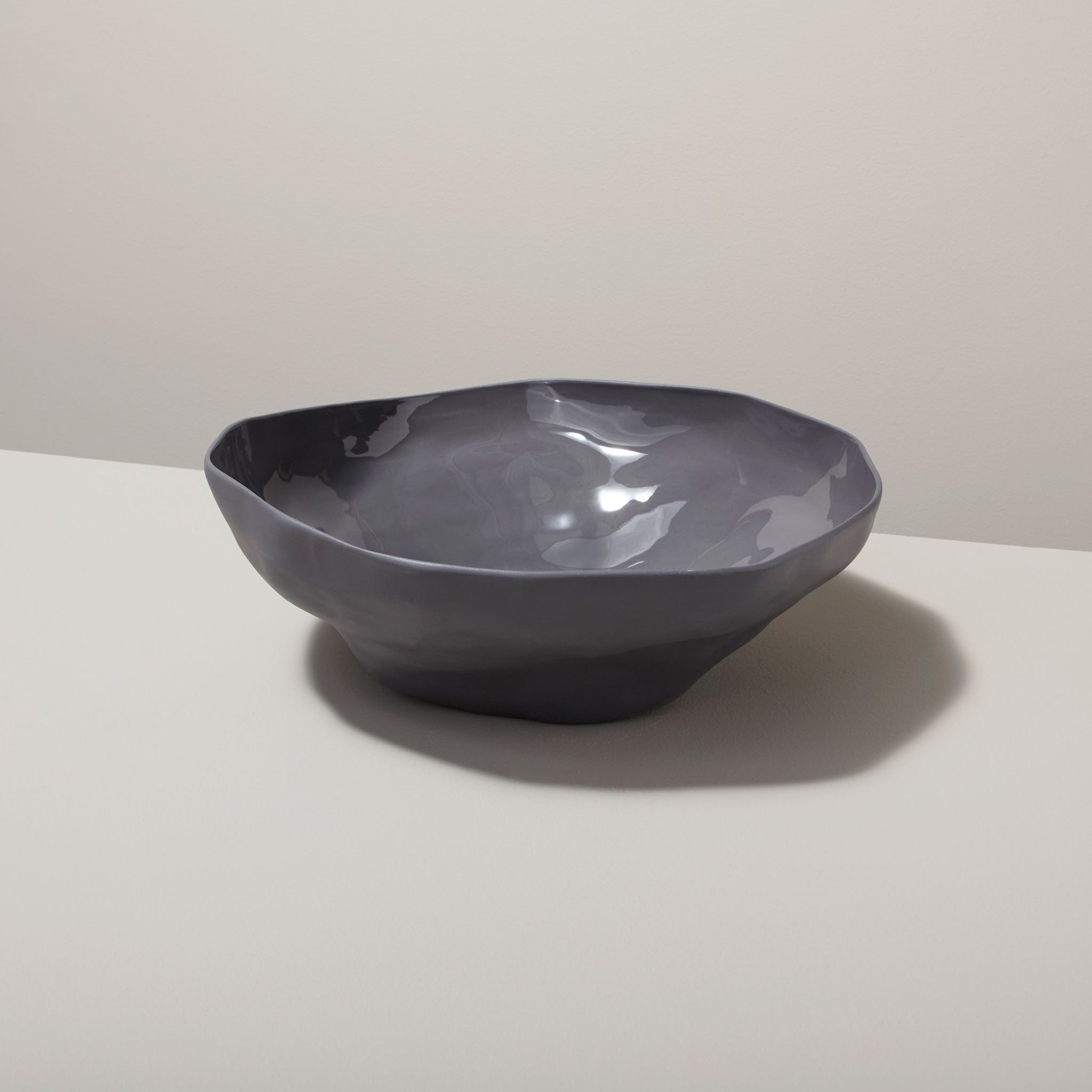 Gray ceramic bowl on a white surface with a light gray background