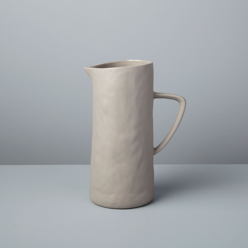 Beige ceramic pitcher on a gray background