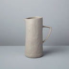 Beige ceramic pitcher on a gray background