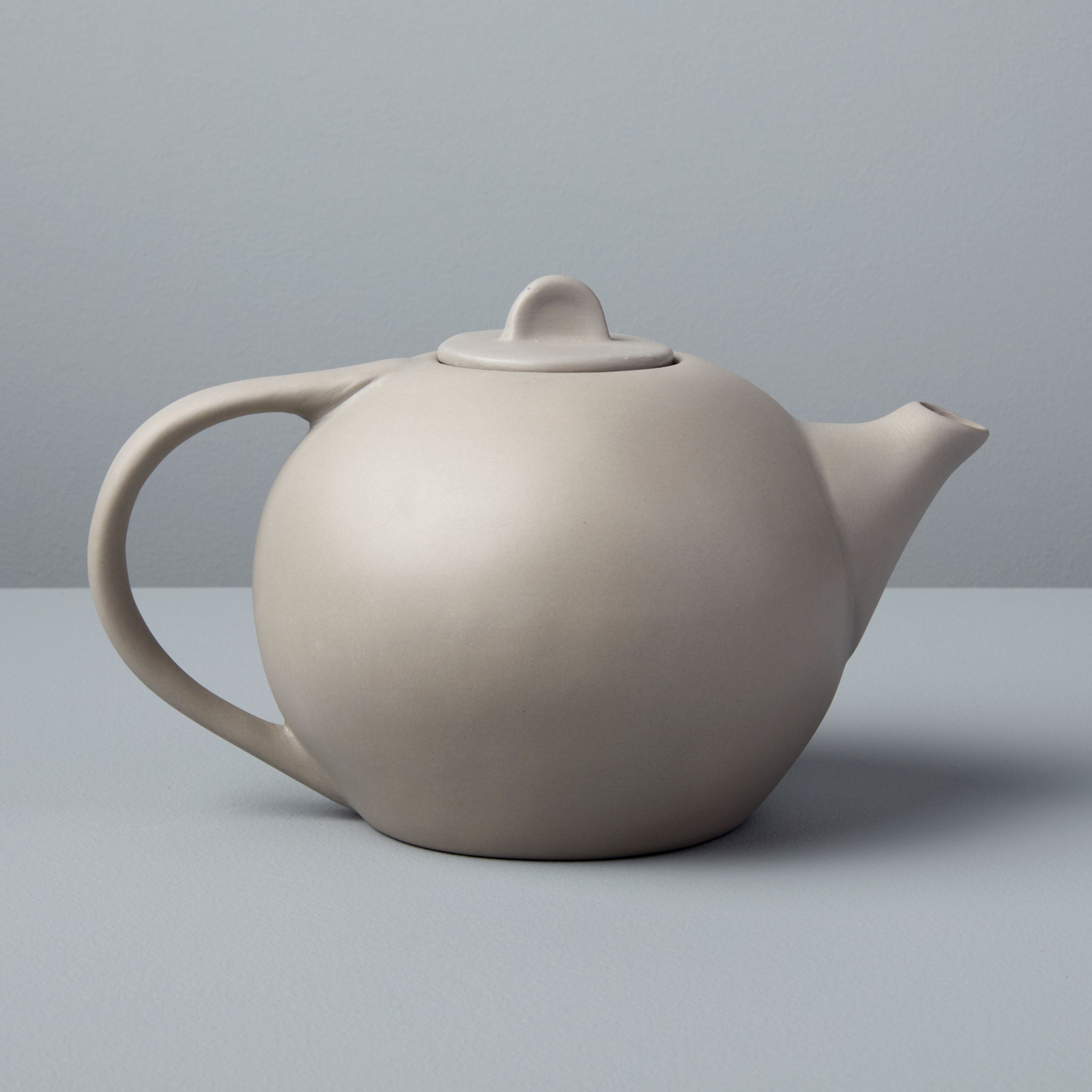 Beige ceramic teapot on a gray background