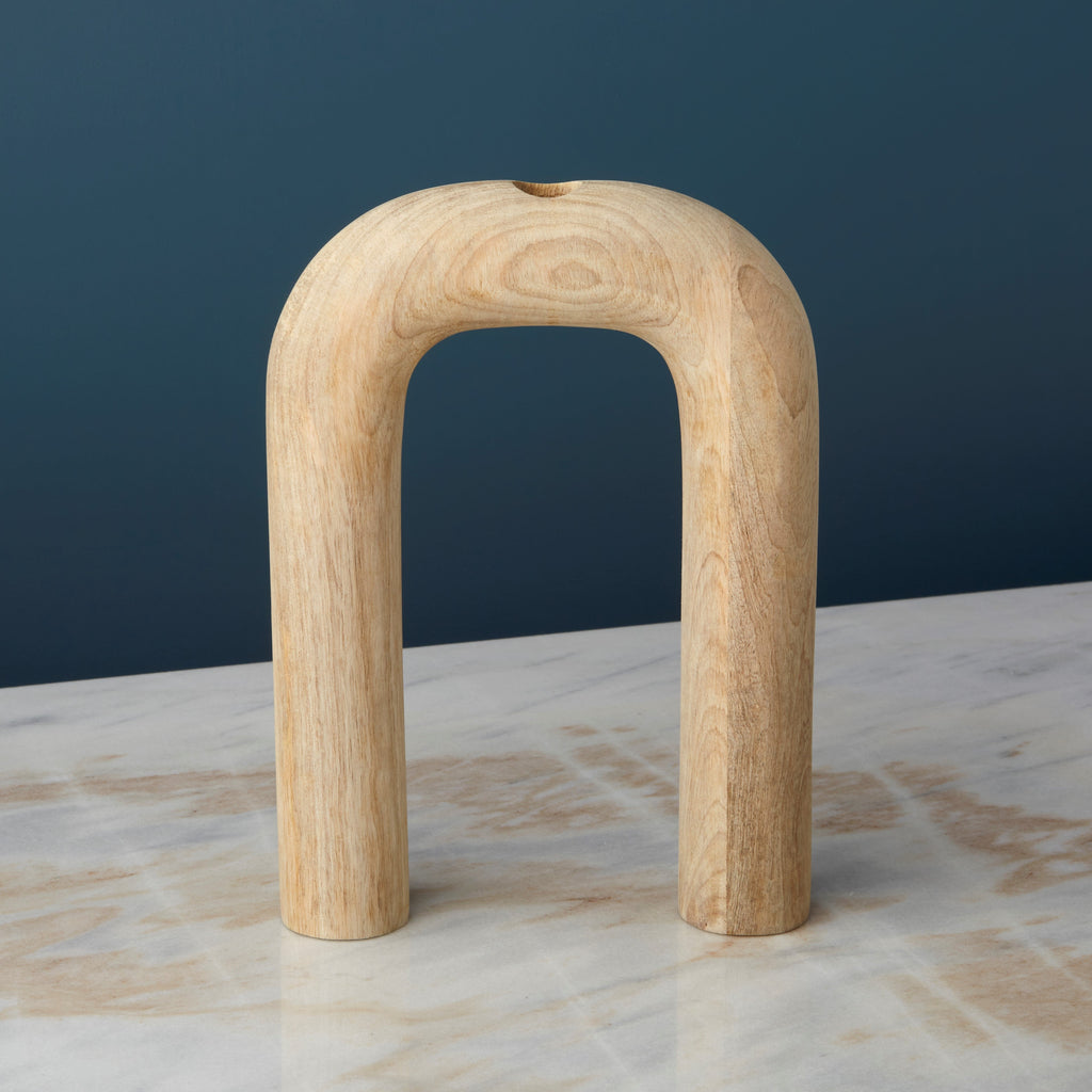 Wooden arch sculpture vase on a marble surface with a dark blue background