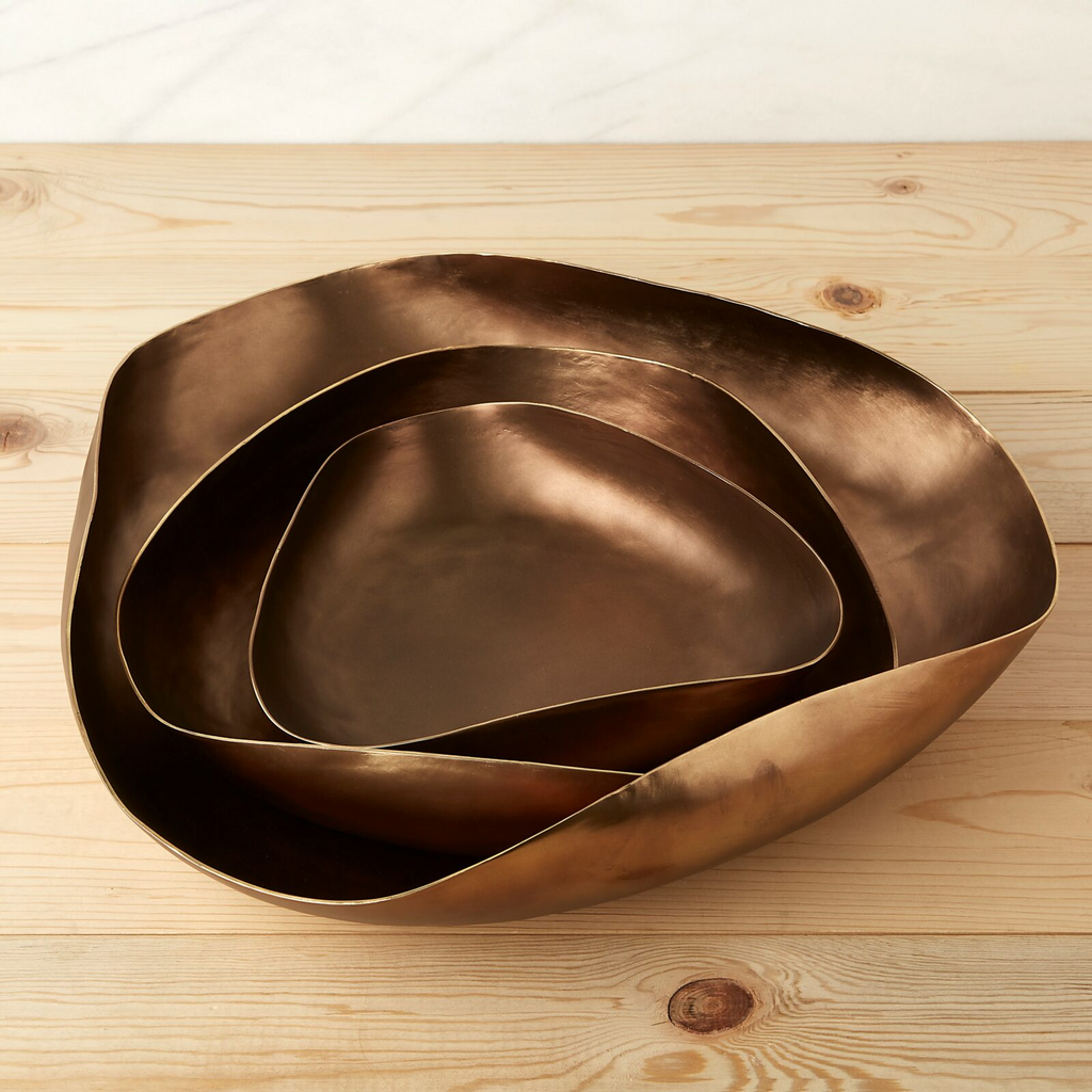 Set of three bronze bowls on a wooden surface