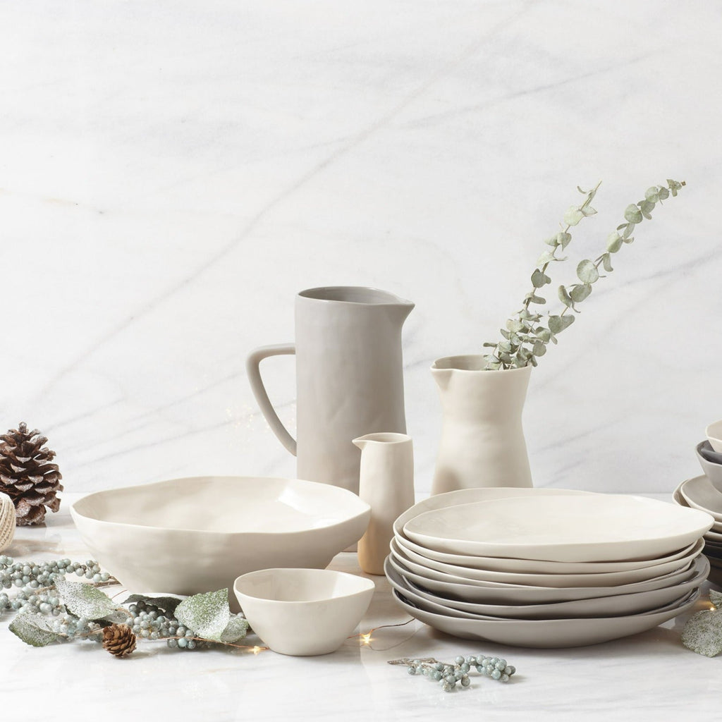 Set of white ceramic dinnerware on a light background with decorative elements.