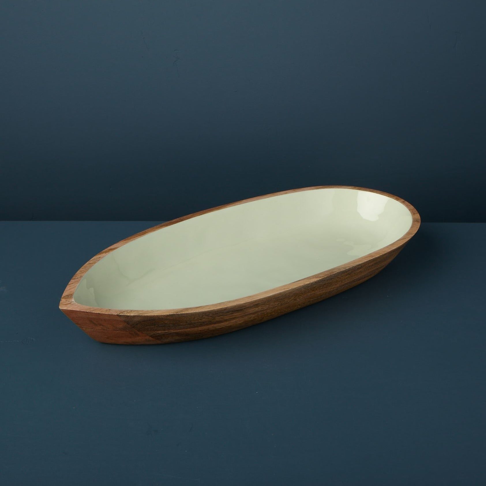 Oval ceramic dish with wooden rim on a dark blue background