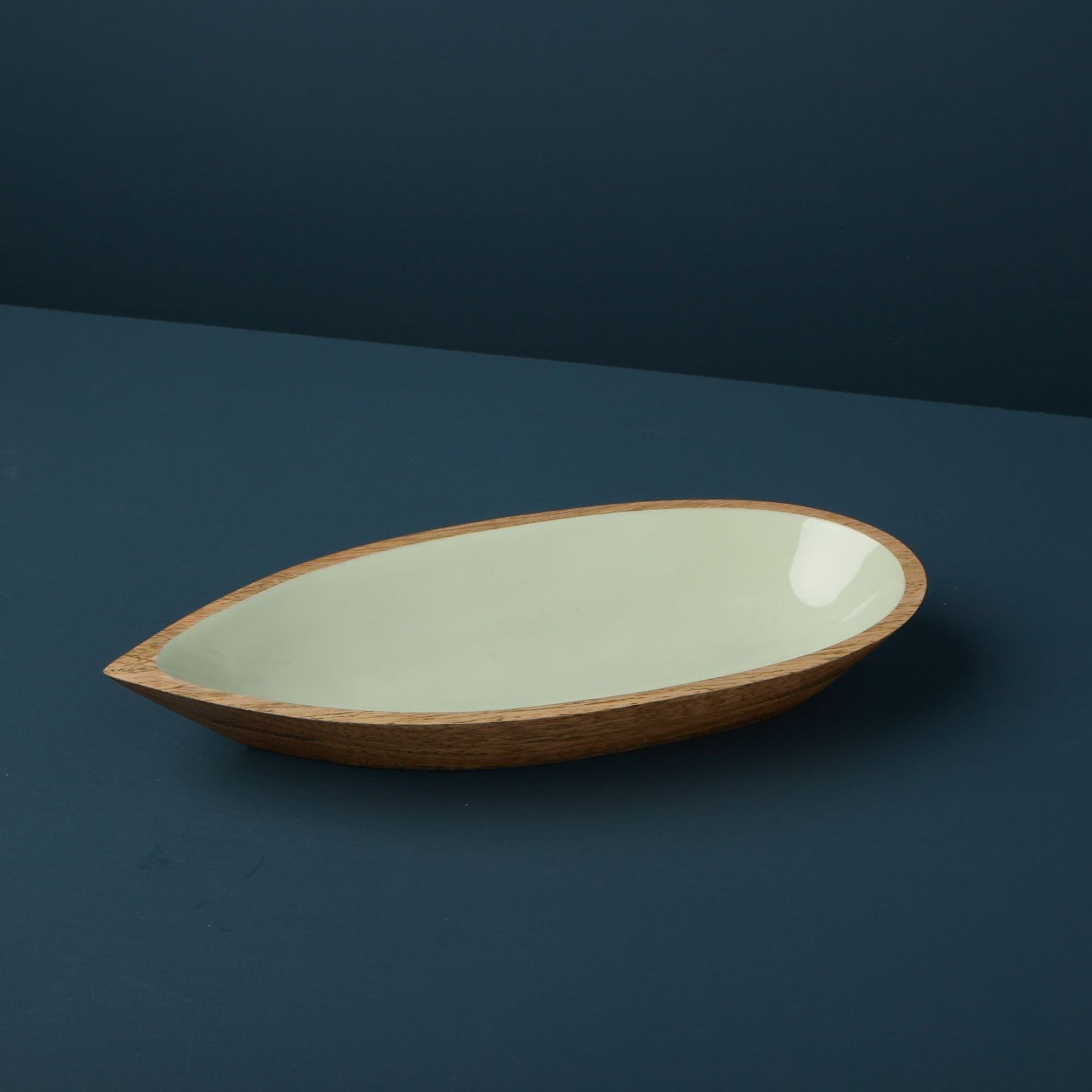 Oval ceramic dish with wooden rim on a dark blue background