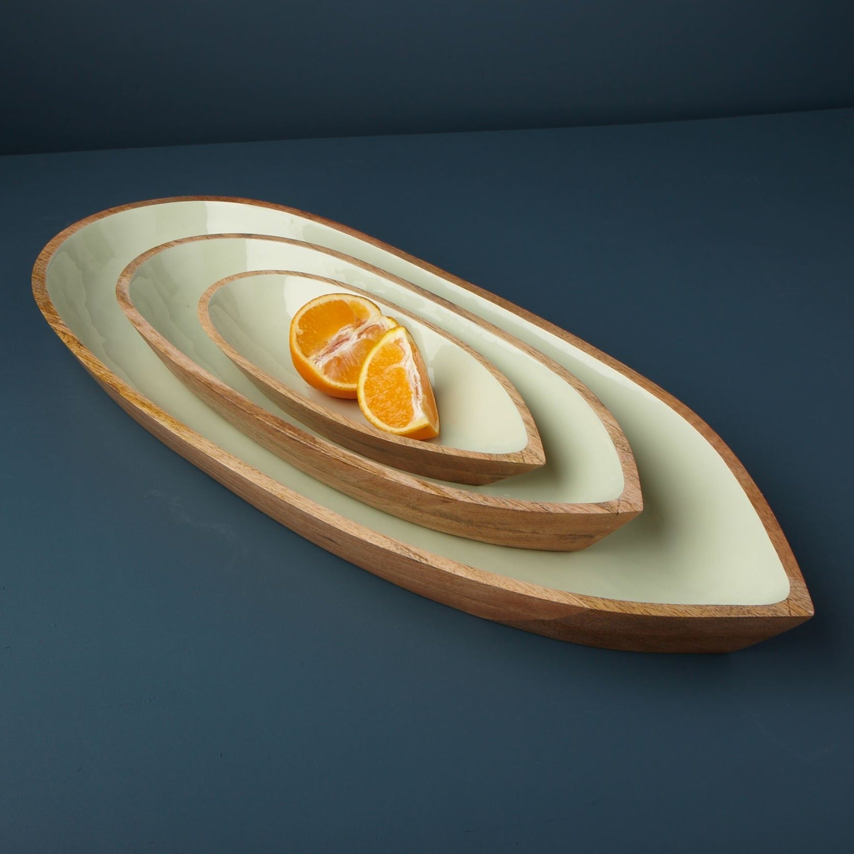Decorative ceramic dish with concentric circles containing sliced oranges on a dark blue background