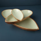 Set of three ceramic leaf-shaped bowls on a dark blue background