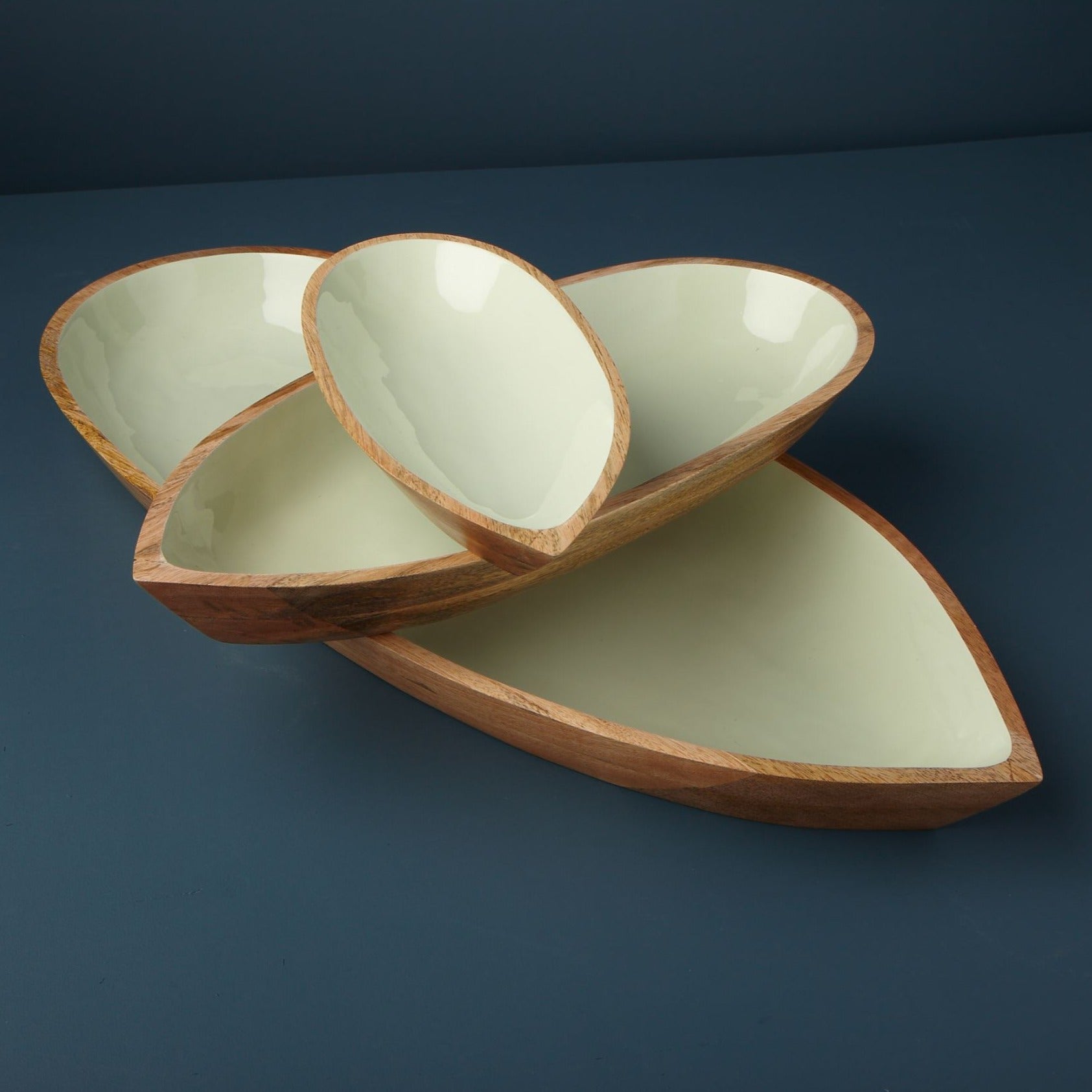 Set of three ceramic leaf-shaped bowls on a dark blue background