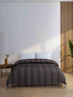 Black king size blanket with tassels on a bed in a modern minimalist bedroom
