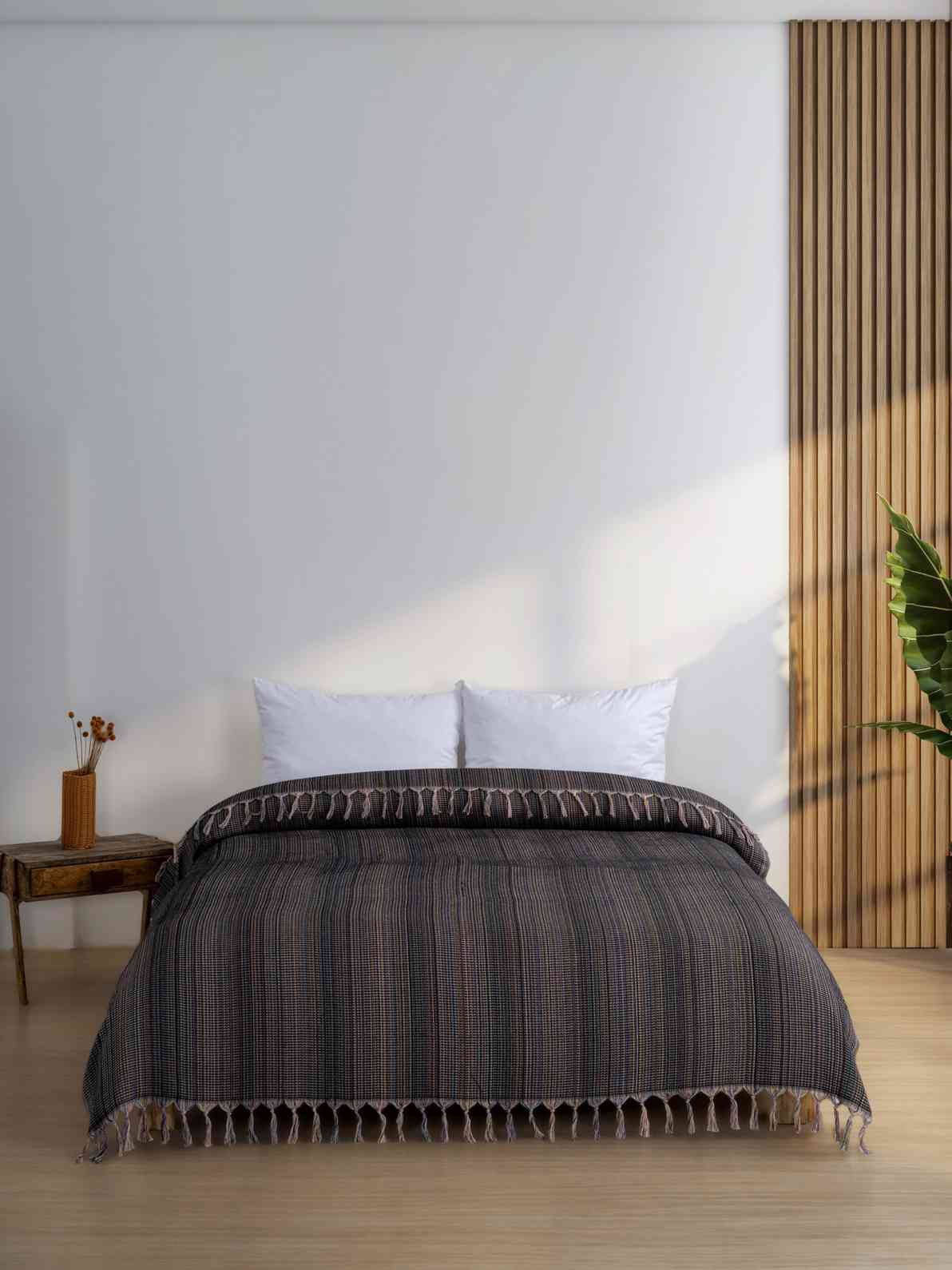 Black king size blanket with tassels on a bed in a modern minimalist bedroom