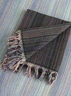Folded black king size blanket with fringe tassels and multicolor woven pattern