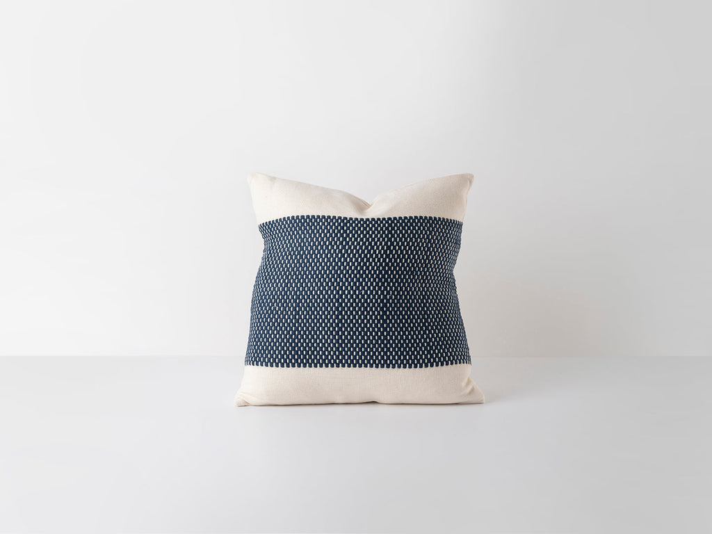 Decorative pillow with black patterned center and white edges on a light gray background