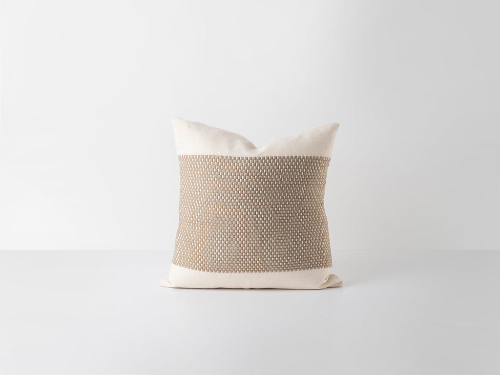 Textured pillow with beige and white color scheme on a light gray background