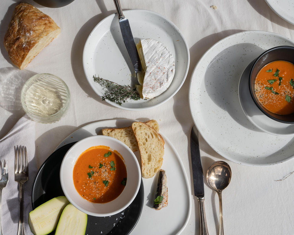 Two bowls of soup with bread and herbs on a white table.