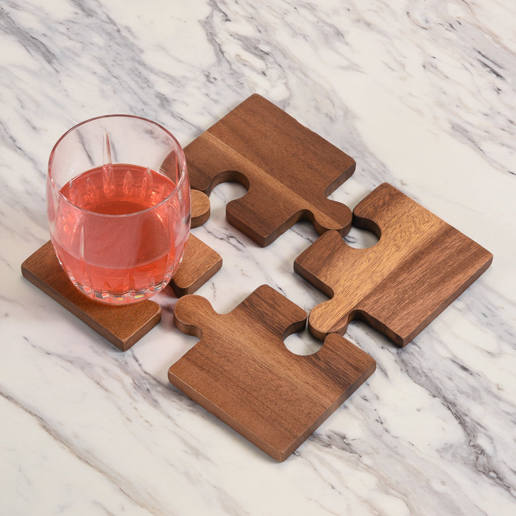 Wooden puzzle piece coasters with a glass of pink drink on a marble surface