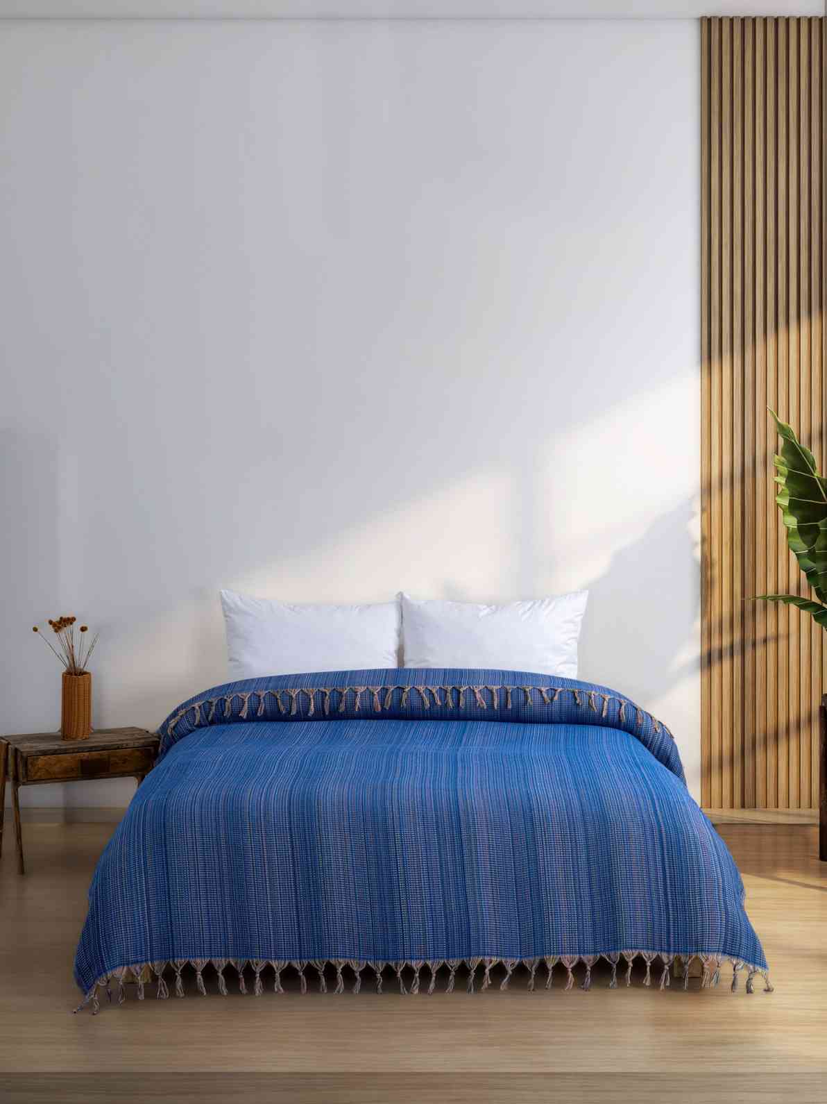 Dark blue king size blanket with tassels on a modern bed in a minimal bedroom