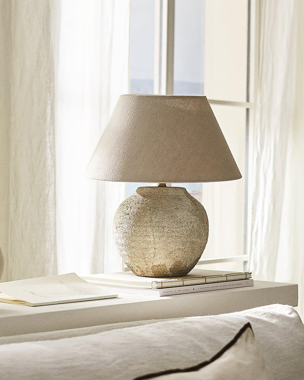Textured table lamp on a surface with a window in the background