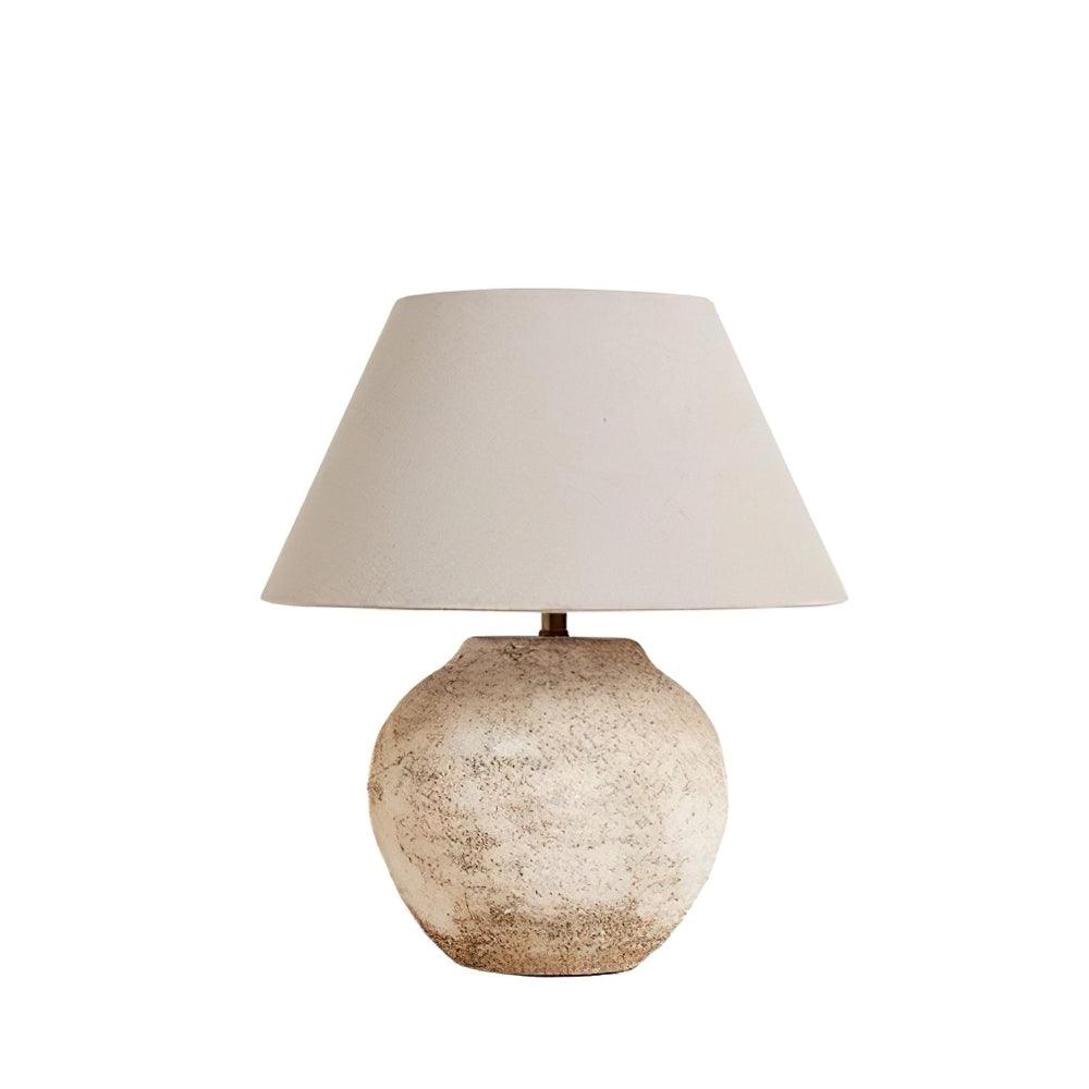 Table lamp with textured base and beige shade on a white background