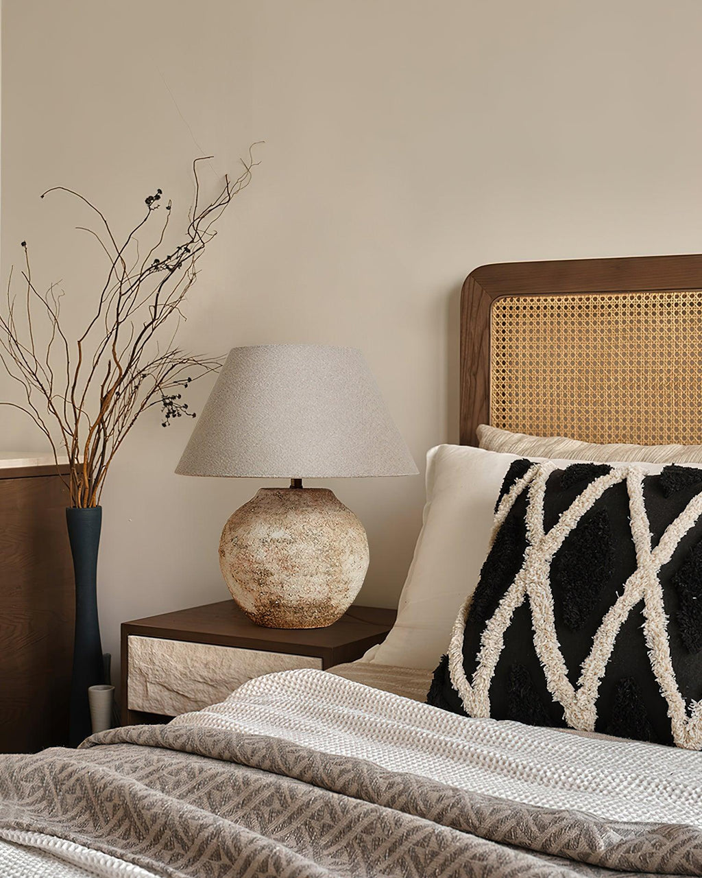 Bedroom with a bed featuring a black and white patterned pillow, a wooden headboard, and a textured lamp on a nightstand.