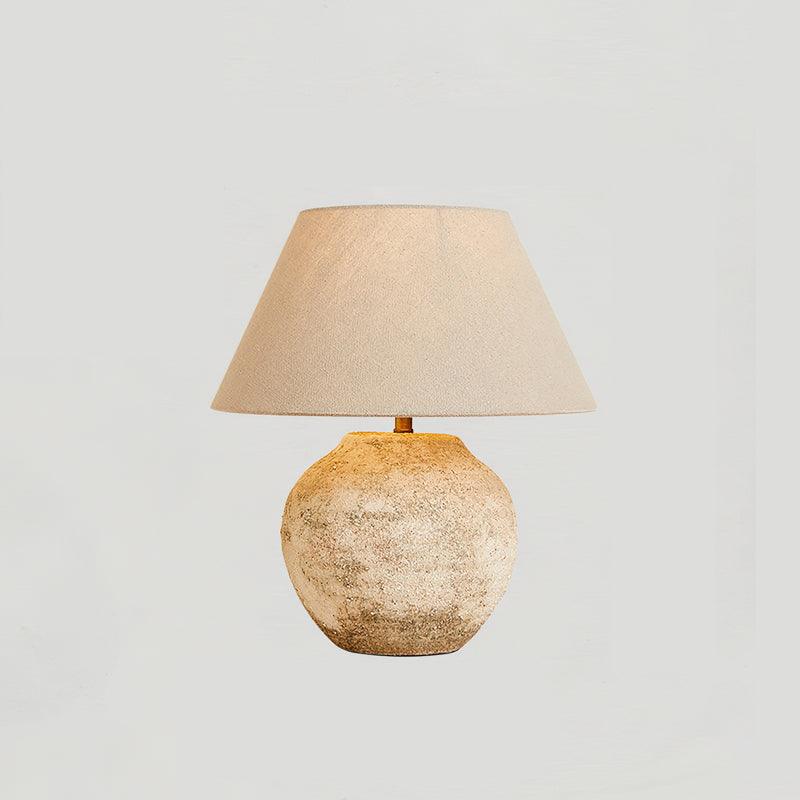 Table lamp with textured base and beige lampshade on a light gray background