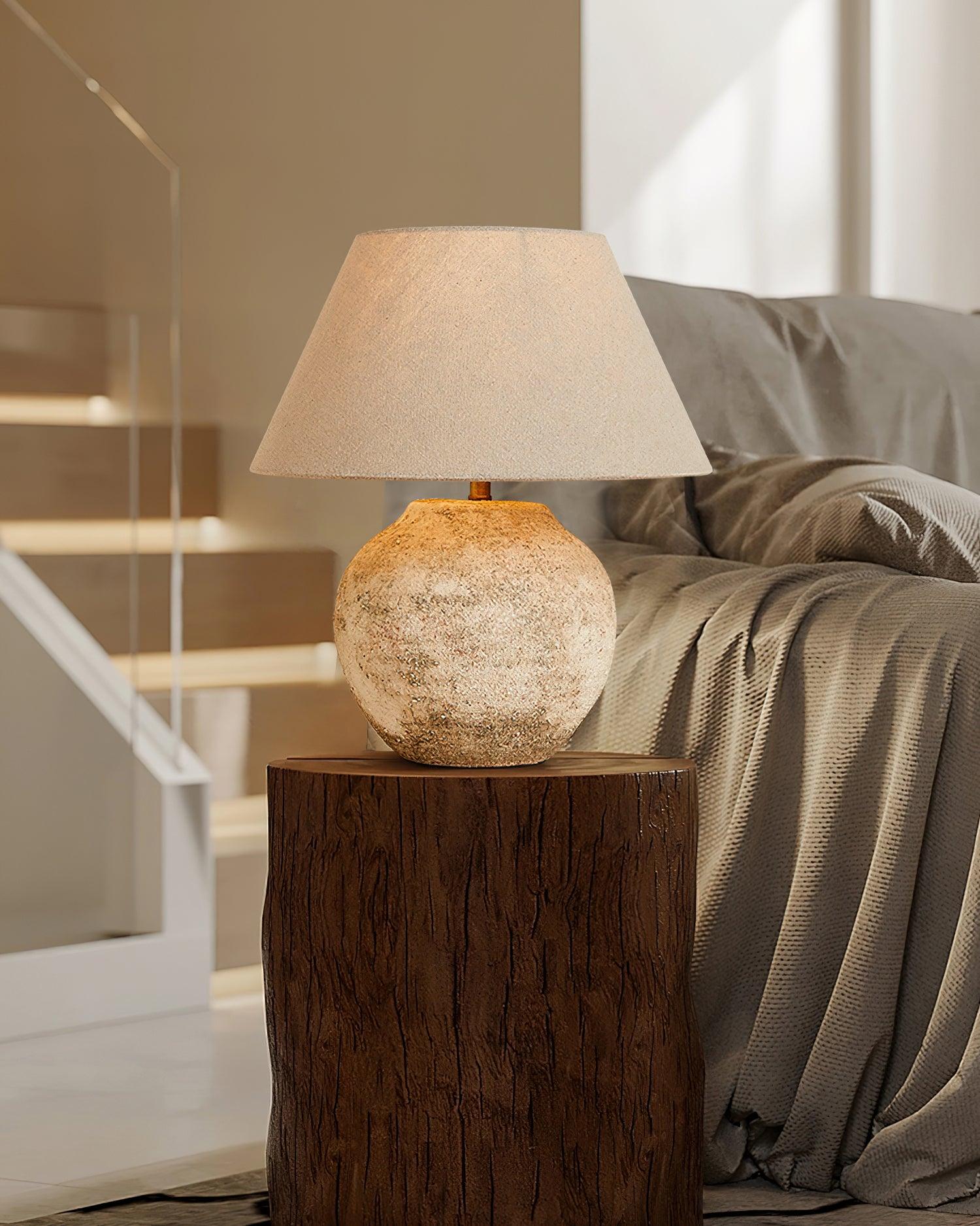 Table lamp with textured base on a wooden side table in a home setting.