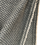 Close-up of a textured black and white patterned rug with a fringe edge.