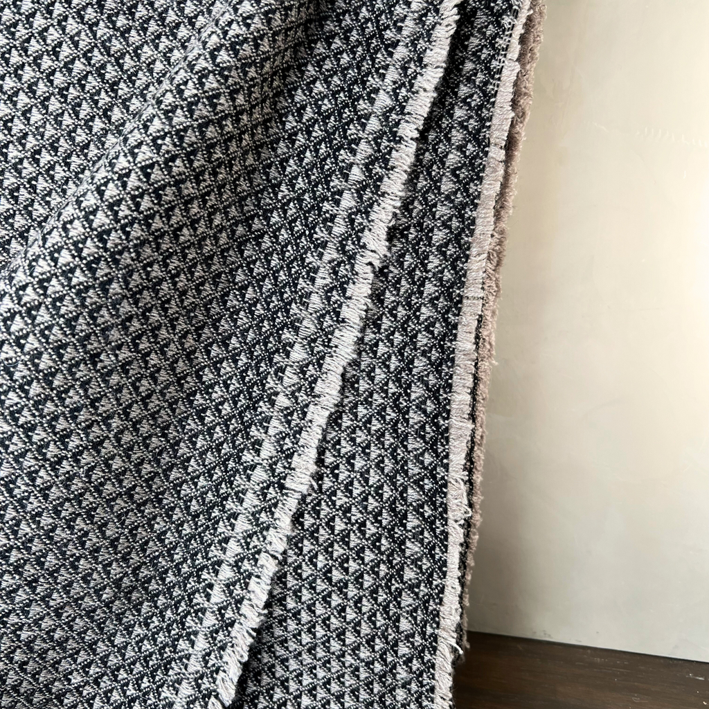 Textured black and white blanket draped over a surface with a neutral background
