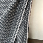 Textured black and white blanket draped over a surface with a neutral background