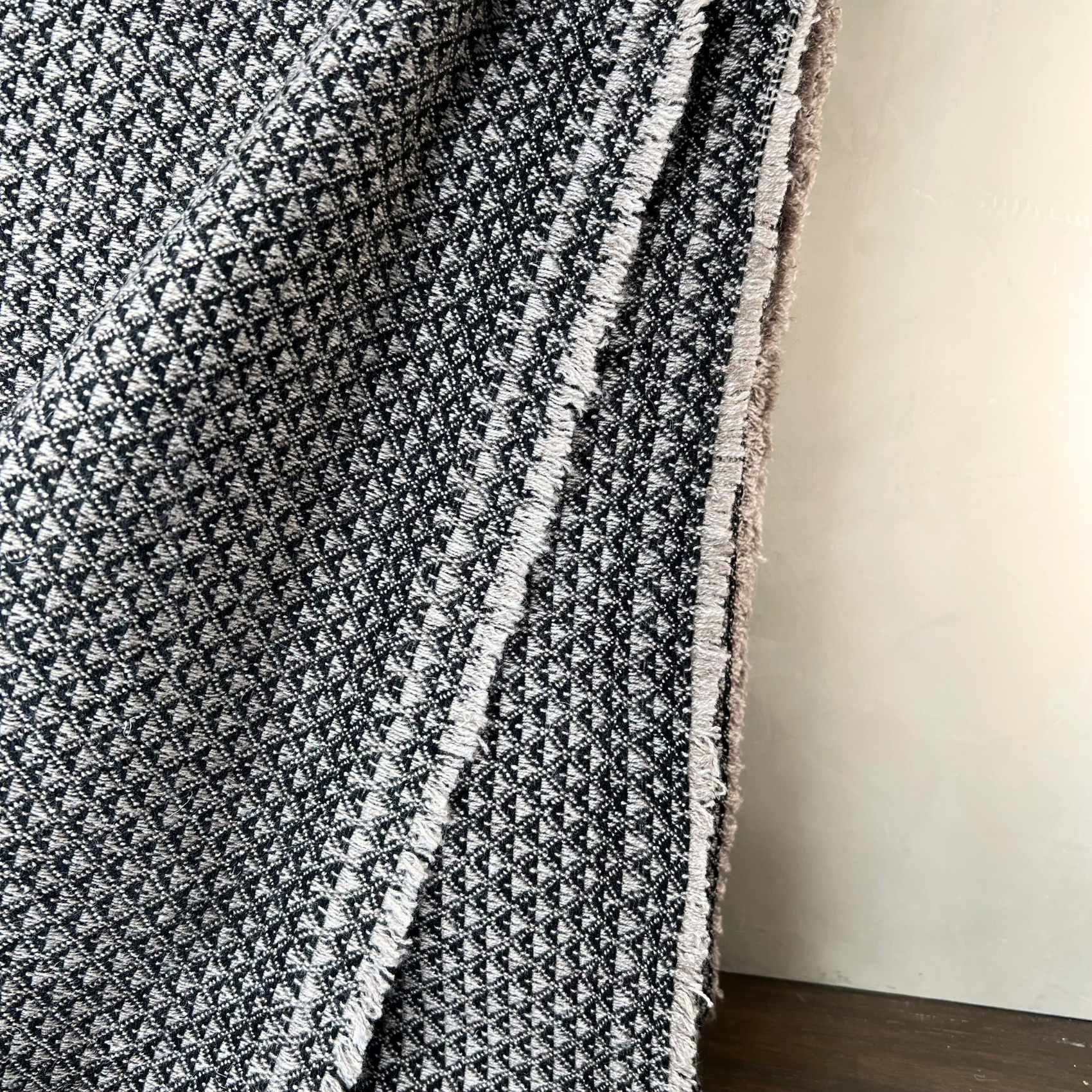 Textured black and white blanket draped over a surface with a neutral background