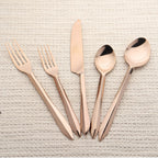 Rose gold cutlery set on a textured beige surface