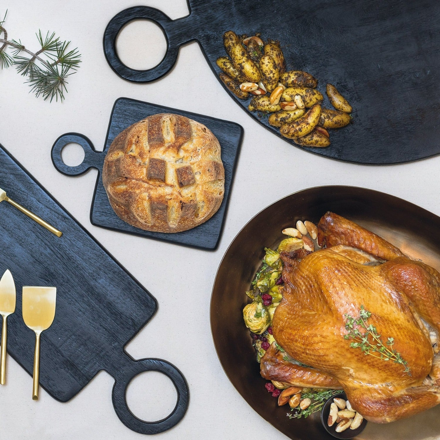 Roasted turkey with garnishes on a platter, surrounded by bread, nuts, and decorative elements on a white surface.