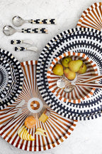 Decorative plates with striped patterns and fruit on a light background