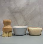 Wooden brush, white container, and beige soap on a marble surface