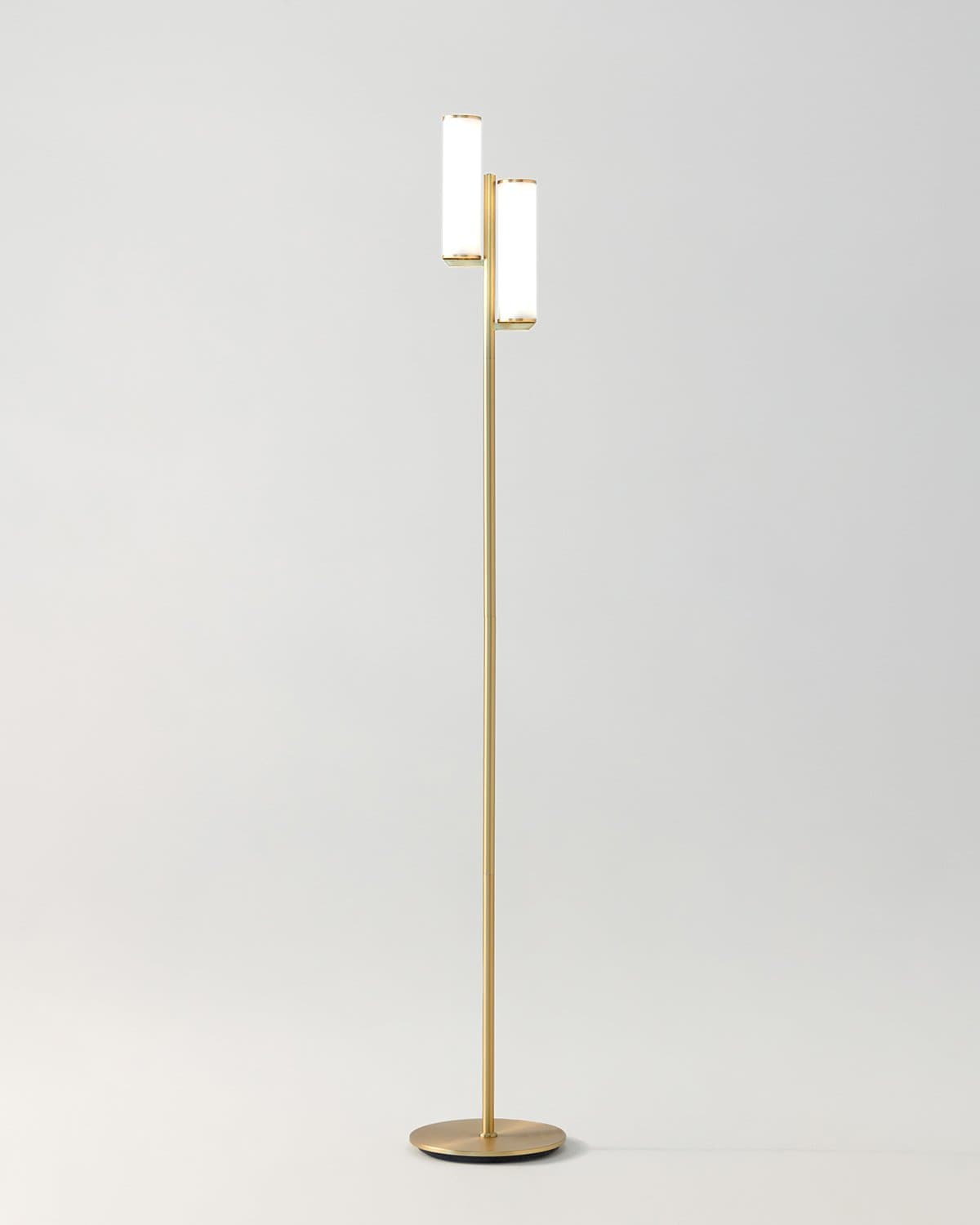 Modern floor lamp with gold base and white shade on a light gray background