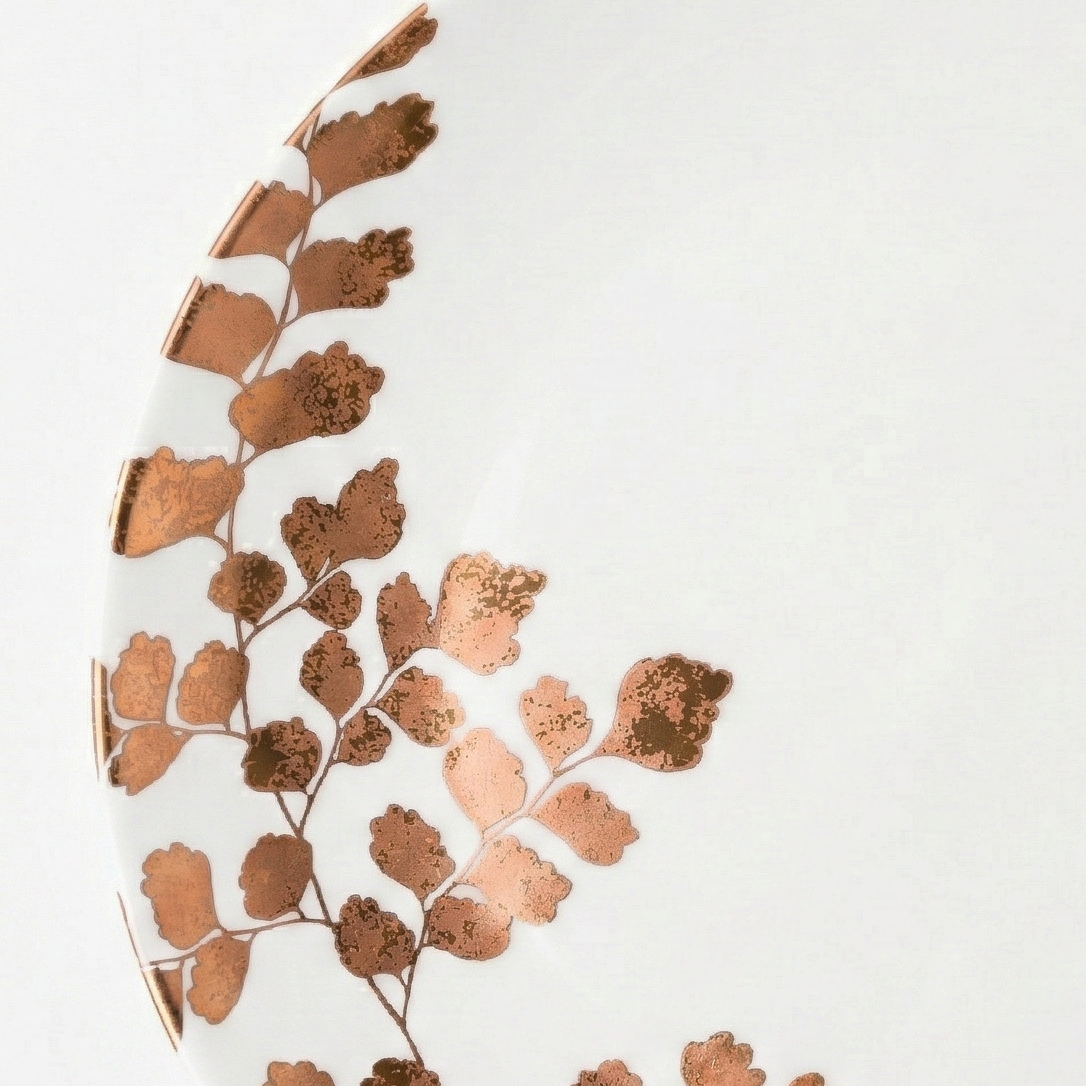 Decorative plate with copper leaf pattern on a white background