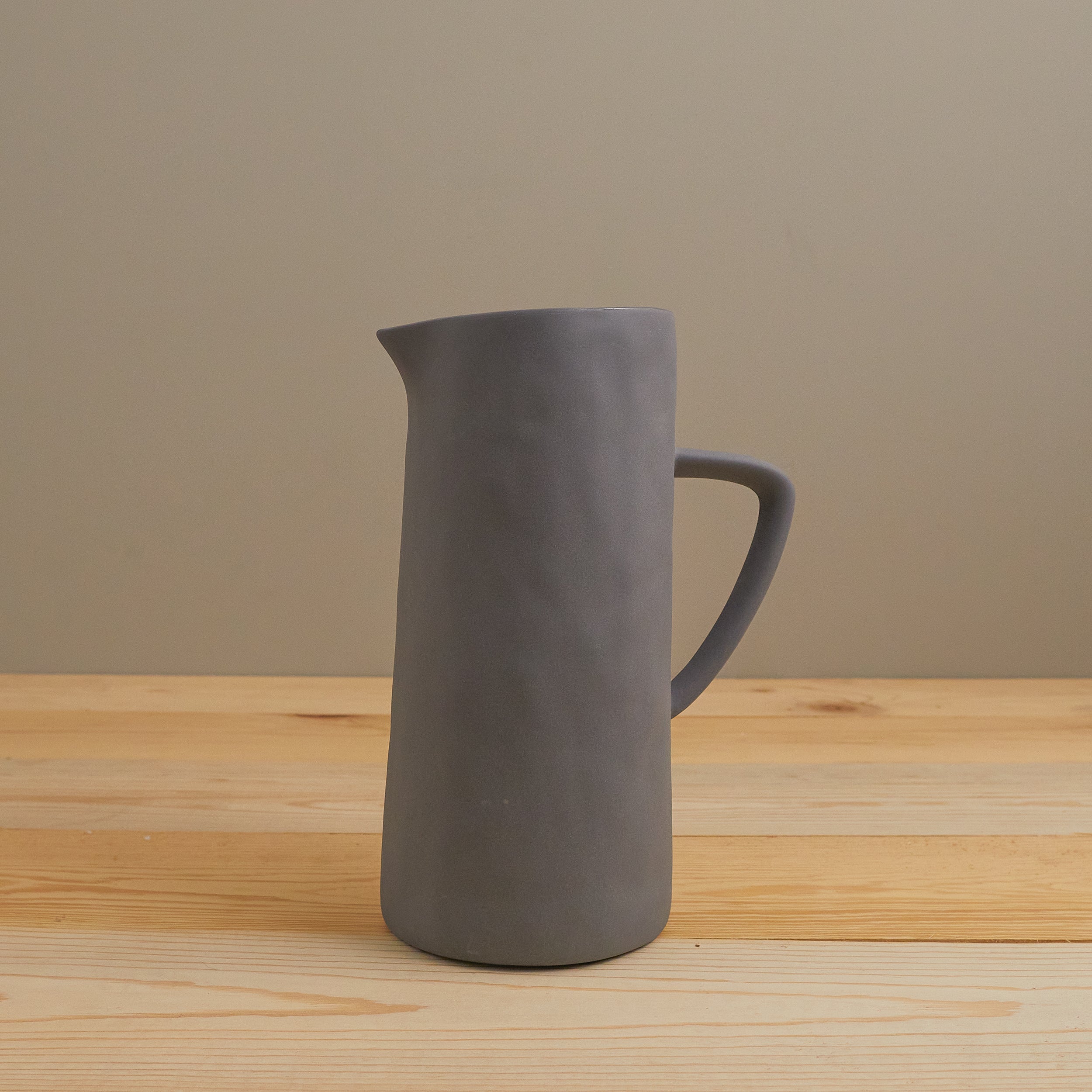 Gray pitcher on a wooden surface with a beige background
