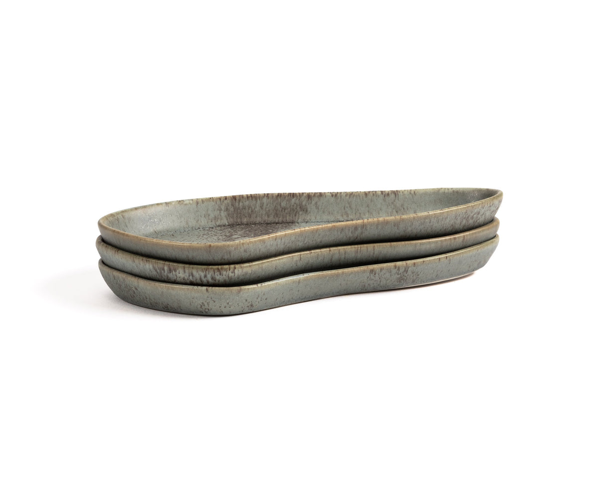 Three oval ceramic trays stacked on a white background
