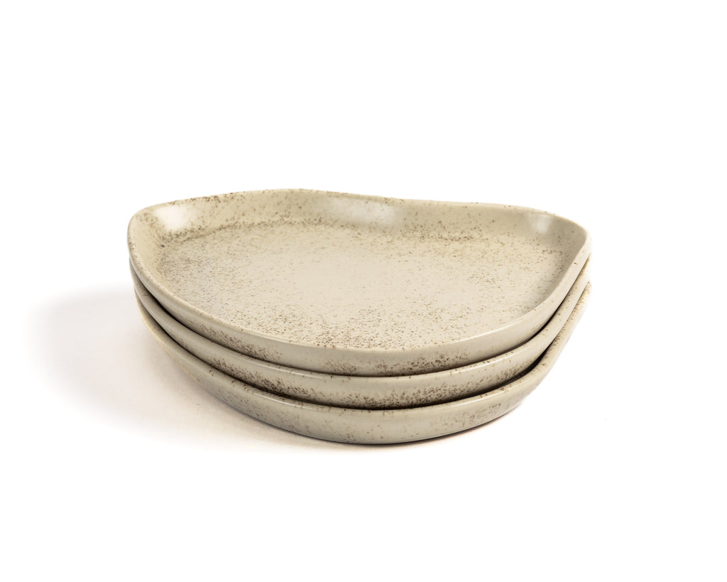 Set of three beige ceramic plates stacked on a white background