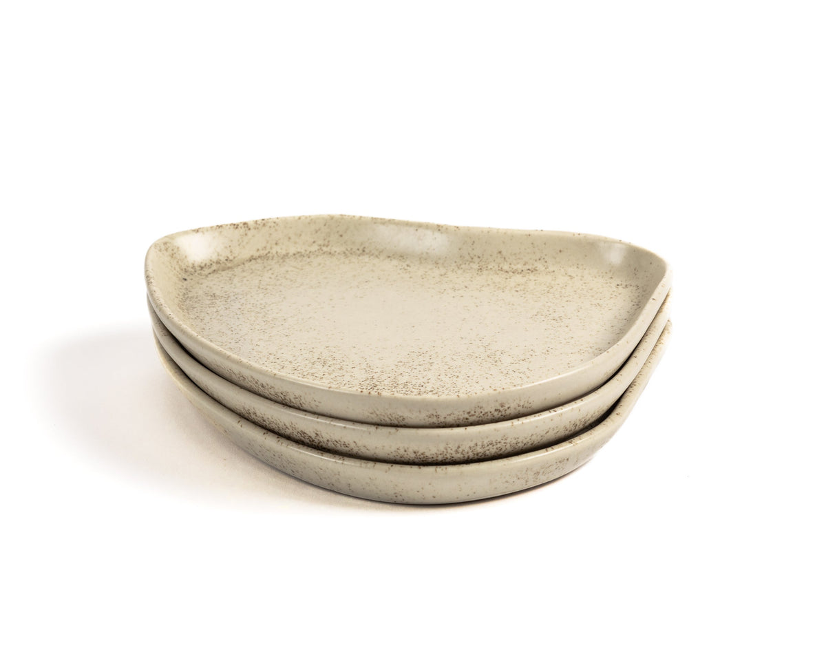 Set of three beige ceramic plates stacked on a white background