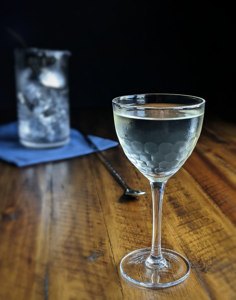 Clear wine cocktail glass with a drink on a wooden table with a dark background