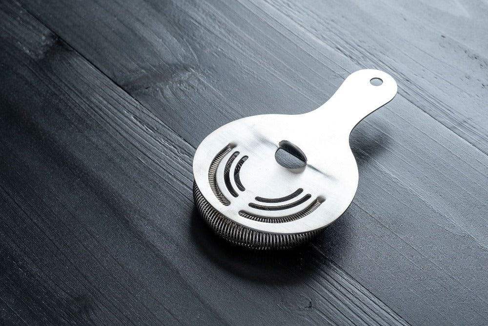 Metallic strainer on a dark wooden surface